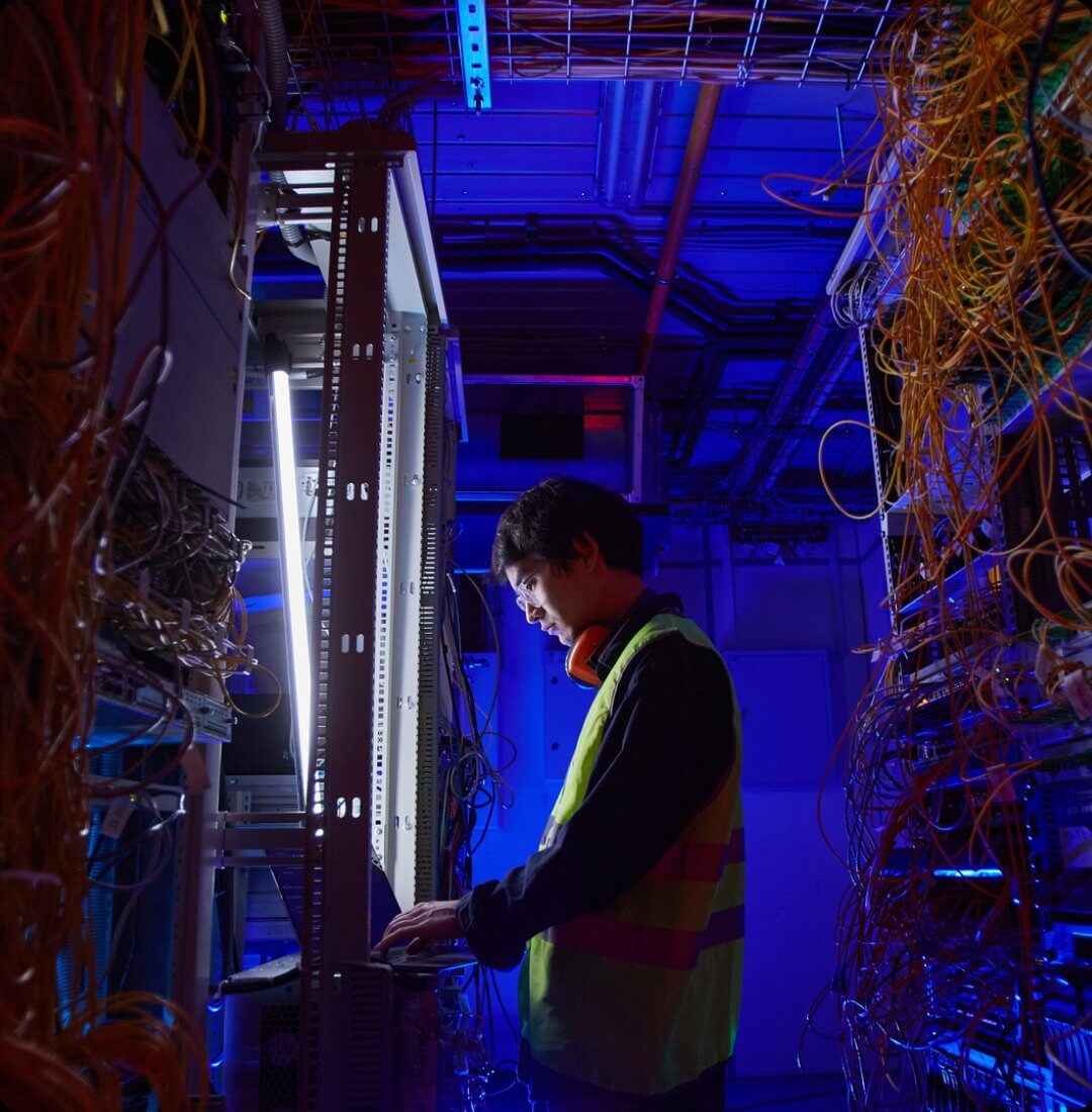 System administrator working in server room with network equipment
