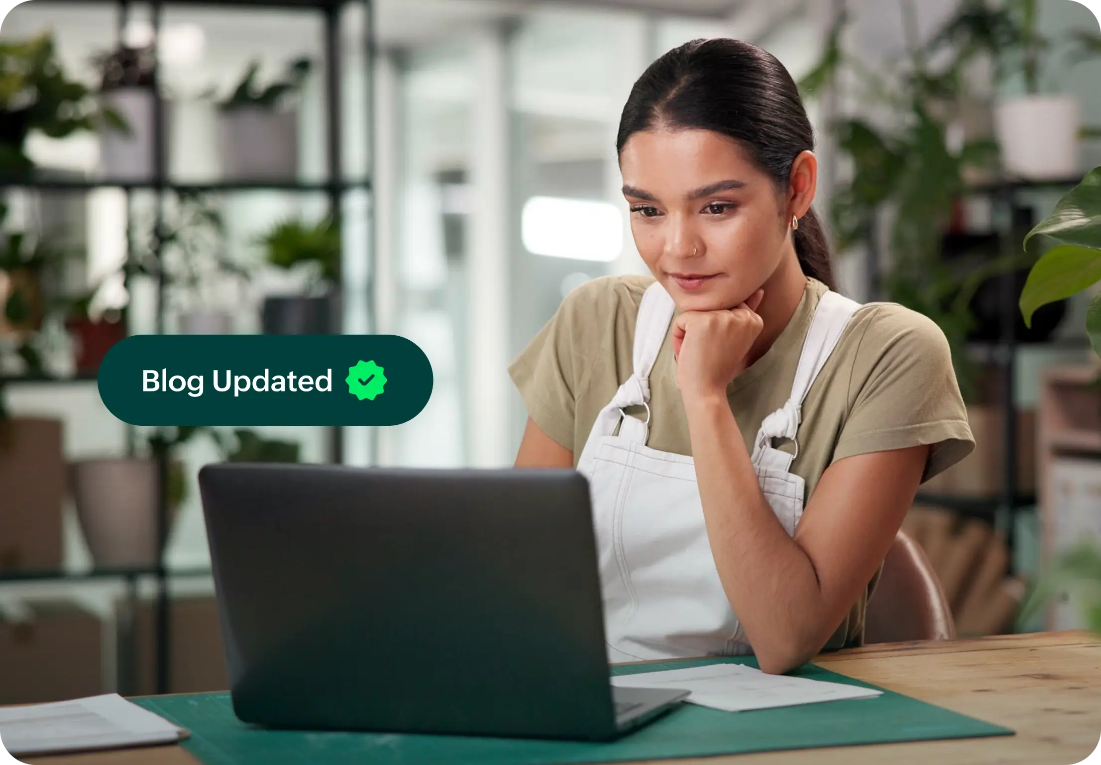 Woman working on laptop with 'Blog Updated' notification.